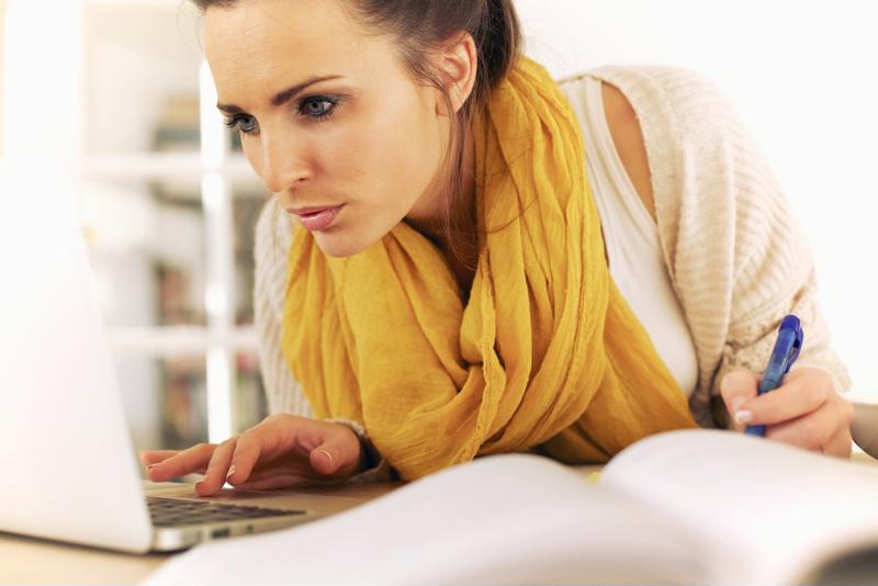 productive woman writing and looking at computer
