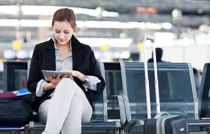woman sitting at an airport looking at tablet