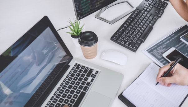 right handed person writing in front of laptop